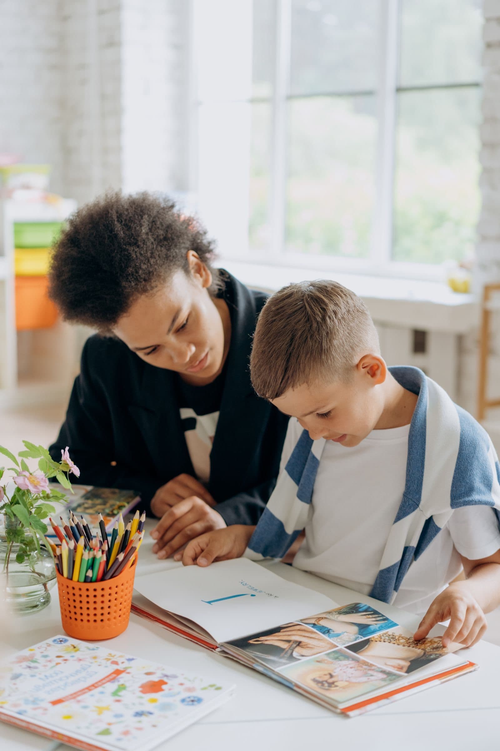A tutor working through a problem with a young student at a table